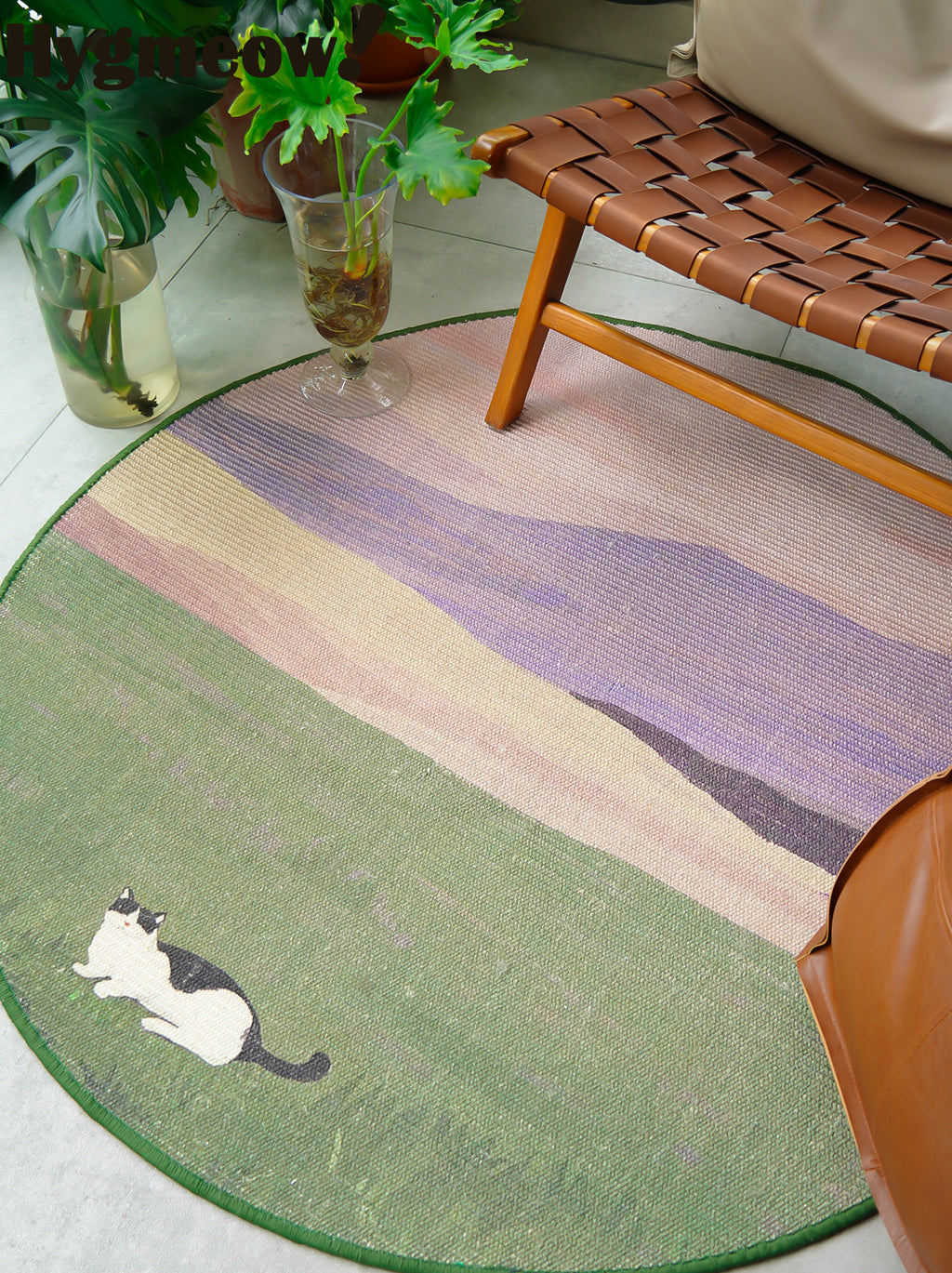 Round multicolored rug with a cat design on a light wooden floor.